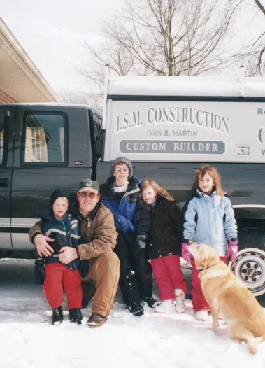 A winter scene showing the ISM Construction owner and his family gathered beside their branded truck.