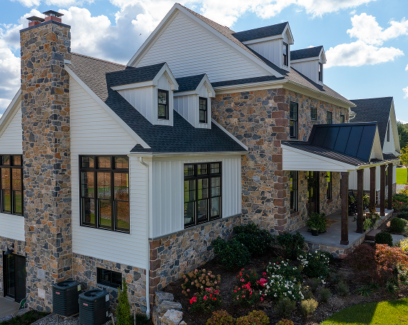 A large stone house featuring a prominent stone chimney against a clear sky.