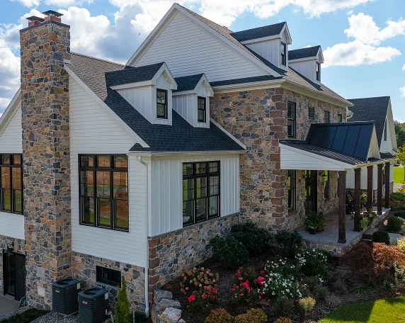 A large stone house featuring a prominent stone chimney against a clear sky.