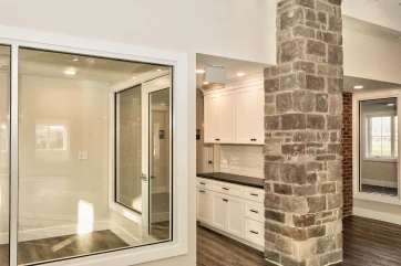 An interior view showing a custom glass viewing window partition and white office cabinetry installed by ISM Construction, a General Contractor in Lebanon, PA.