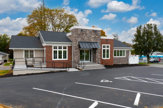 Exterior facade of a modern commercial office building featuring brick and stone masonry with a fresh asphalt parking lot, completed by ISM Construction, a General Contractor in Lebanon, PA.
