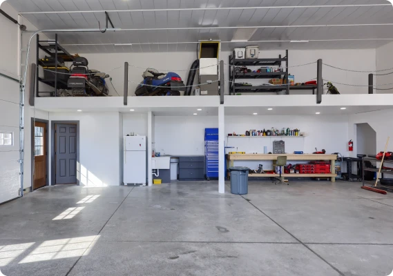 Spacious interior of a custom workshop garage featuring concrete floors, a work bench area, and an overhead storage mezzanine level, completed by ISM Construction, specialized in Custom Garages in Lebanon, PA.