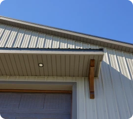 Close-up architectural detail of a gabled roofline with vertical metal siding, custom soffits, and integrated exterior lighting, crafted by ISM Construction, experts in Custom Garages in Lebanon, PA.