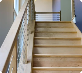 Modern wooden staircase with a sleek wire railing system built by ISM Construction for Second-Story Additions in Lebanon, PA.