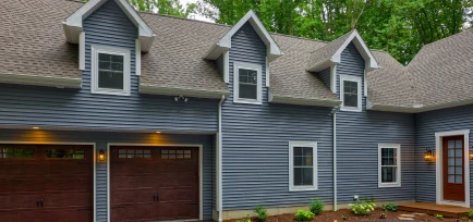 A two-story home with blue siding featuring integrated multi-car attached garages, professionally constructed by ISM Construction, a premier builder of Custom Garages in Lebanon, PA.