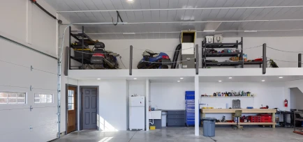 Spacious interior of a custom garage workshop complete with an overhead storage mezzanine and tools, designed by ISM Construction for Custom Garages in Lebanon, PA.
