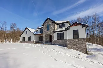 A large house surrounded by a blanket of snow covering the ground, creating a serene winter landscape.