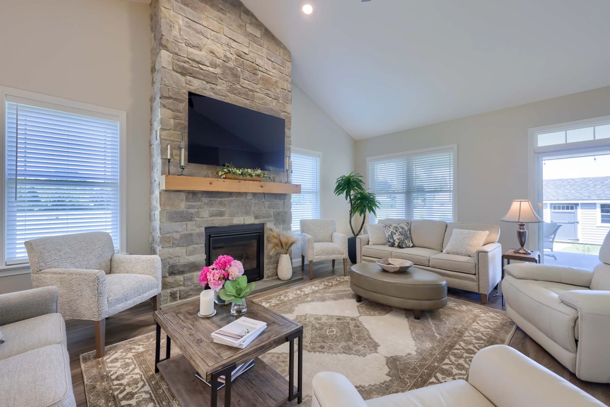 A cozy living room featuring a stone fireplace and a flat screen TV mounted on the wall.
